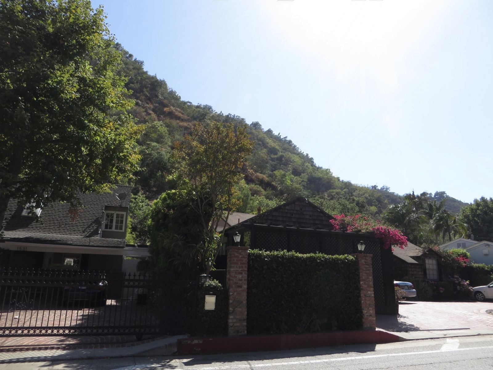 Gated hillside home with a hedge and mountain backdrop in Bel Air, Los Angeles