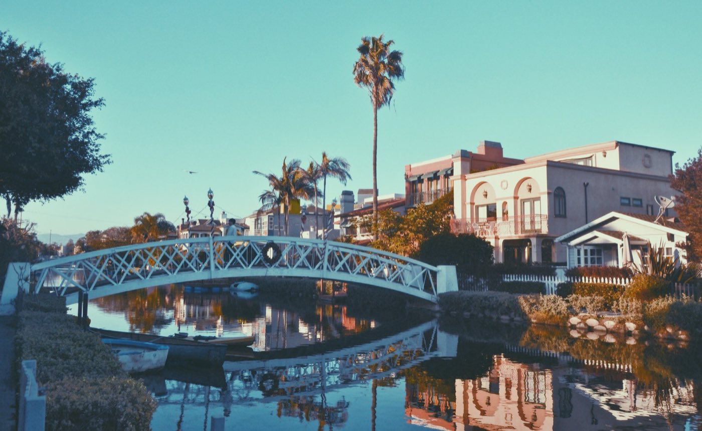 White bridge over the Venice Canals with Mediterranean-style homes and palm trees